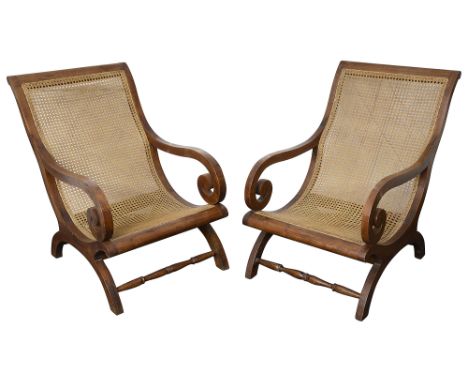 A pair of mid 20th century colonial planter chairs Indian teak planter armchairs, with scrolling back and arms, raised on arc