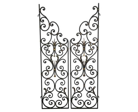 A pair of wrought iron garden gates, black painted, of scrollwork design, with gilt acanthus leaf and flamiform finial adornm
