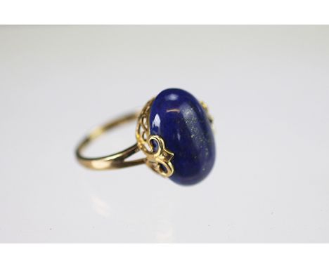 A lapis lazuli set dress ring, the central oval stone within decorative 9ct yellow gold setting and plain hoop, weight 4.8gms