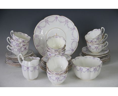 A porcelain tea service, early 20th century, decorated in the 'Waldorf' pattern with purple printed garlands of flowers withi