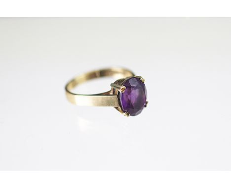 An amethyst set ring, the single oval amethyst with double four claw setting and broad hoop, all set in 9ct yellow gold, weig