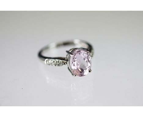 A kunzite and diamond ring, the central oval kunzite claw set in 9k white gold to the diamond set shoulders, weight 3.4gms