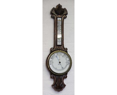 A Victorian carved oak aneroid barometer, the ceramic dial signed Taylor Whitchurch, with inset thermometer above, 81cm