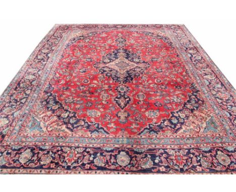 A large Persian hand woven wool carpet, worked with an all over foliate design and a central oval medallion against a red gro