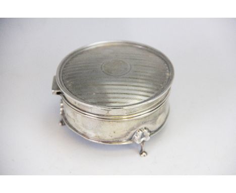 A silver circular box, Birmingham 1916, the hinged cover with engine turned striped decoration and raised on three bracket le