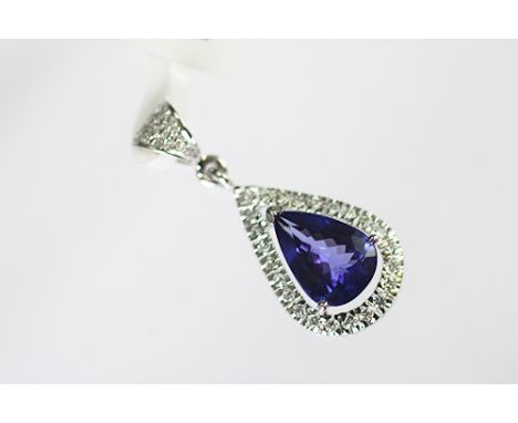 A tanzanite and diamond pendant set in 18k white gold, the pear shaped tanzanite (untested) within a surround of brilliant cu