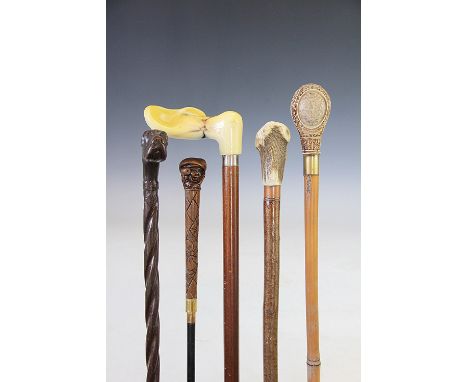 A collection of five walking sticks, to include; a dogs head carved example inscribed St Helena 1901, a Japanese box wood net