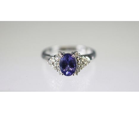 A tanzanite and diamond ring set in 18k white gold, the oval shaped tanzanite (untested) within a surround of sixteen brillia