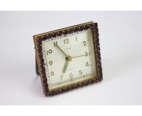 A paste set bedside timepiece by LSM, the square dial with a surround of purple paste stones, folding support, 5.8cm high 
