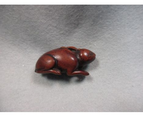 An 18th century wooden netsuke carved as a hare, the animal carved in reclining position, the himotoshi through its stomach, 