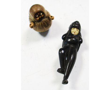 A Kobe Daruma toy and a lion masked man netsuke, the first depicting the monk wrapped in his robes, his eyes and tongue poppi