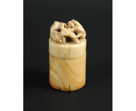An 18th/19th century ivory cylindrical box seal, the screw top pierced and carved with two Buddhist lions playing with a broc