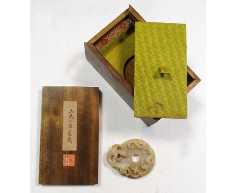 A wooden boxed Han dynasty jade dragon bi, the green stone with a dusting of brown, one side carved in low relief with six ra