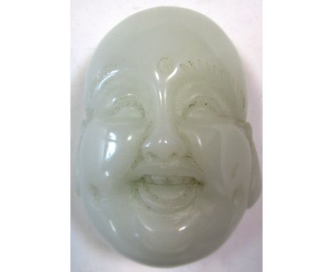 A pale nephrite jade Budai mask toggle, a third eye carved centrally to his forehead as he laughs, long ear lobes flanking hi