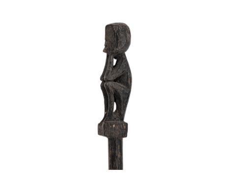 A DAYAK CARVED WOOD TUN TUN 'PIG STICK'
The finial carved with a seated ancestral figure, above a tapering stem
49cm long
Con