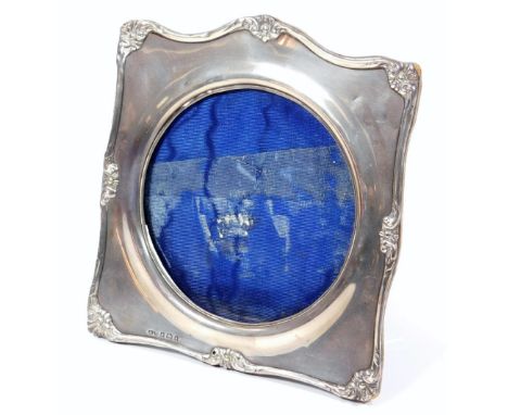 An Edwardian silver photograph frame, of shaped form with a scroll border broken by shells, with an easel back, Birmingham 19