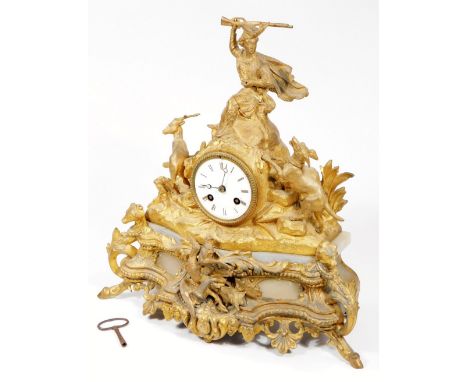 A 19thC gilt metal mantel clock, surmounted by a highland figure, flanked by dog and stag in a naturalistic setting, with 8cm