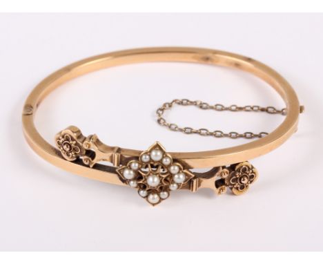 A Victorian yellow metal hinged bangle with central seed pearl cluster, 9.9g 