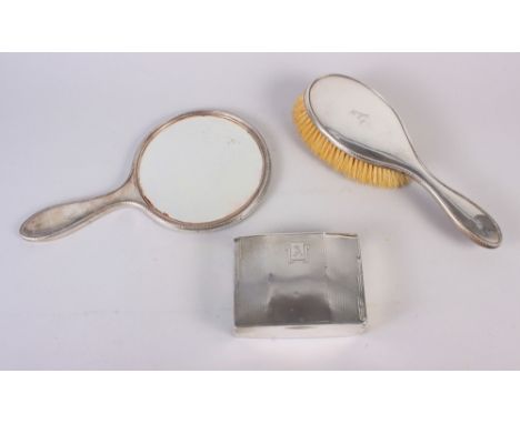 An engine turned silver cigarette box, a silver dressing table mirror and a matching hairbrush 