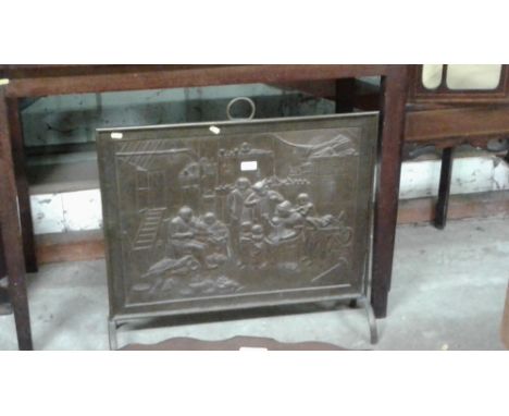A brass embossed firescreen depicting figures in a tavern