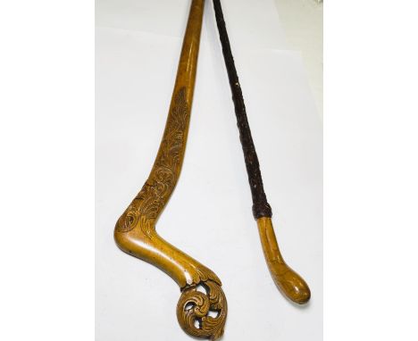 An unusual stick, possibly late 19th Century, with scroll and pierced finial, and scrollwork shoulders, 95cm, and another sti