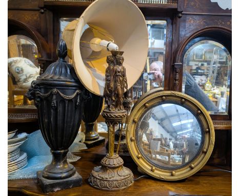A classical-style lamp with three females, a black lidded urn and a convex gilt framed mirror.