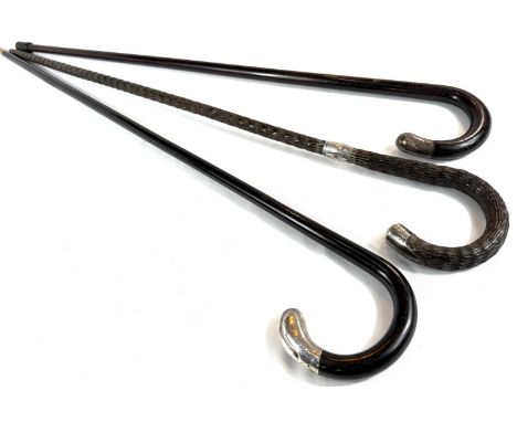 An Edwardian ebonised walking stick with inlaid silver ribbon work and finial, 84cms, and two other similar sticks (3).