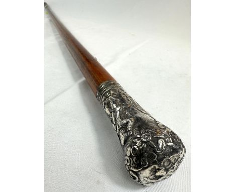 A 19th Century Malacca walking stick with white metal finial embossed with figures, probably Dutch, 95cm.