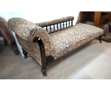 An ebonised framed spindle back chaise longue in floral tapestry upholstery.