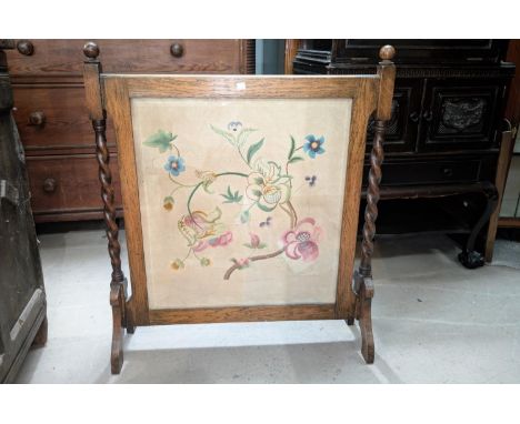 An oak framed tapestry fire screen with floral decoration.