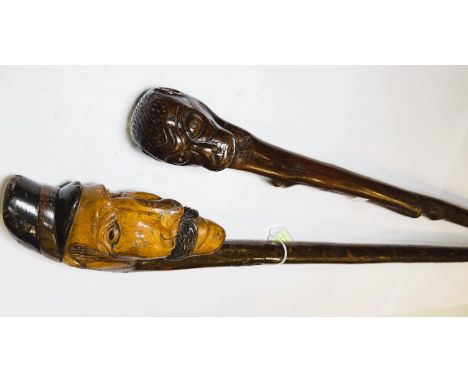 An early 20th Century continental stick with carved head finial, 109cm, and another with ape finial, 95cm (2).