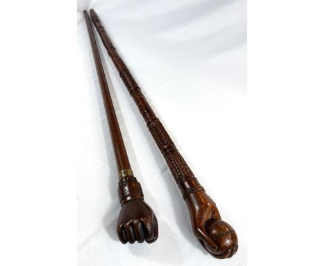 A vintage carved hardwood stick of Asian origin, the finial with hand clasping a cricket ball, 91cm, and another (2).
