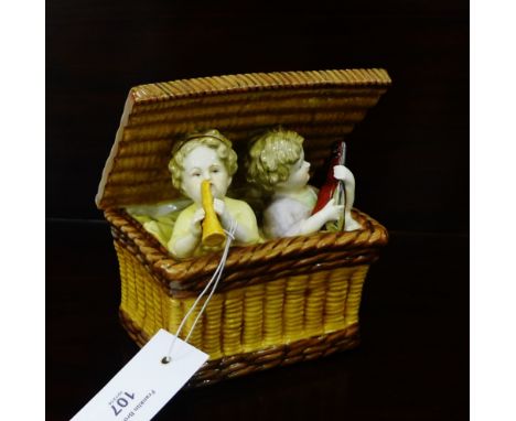 A continental porcelain figure group depicting two cherubs playing instruments within a wicker basket, 16 x 14cm