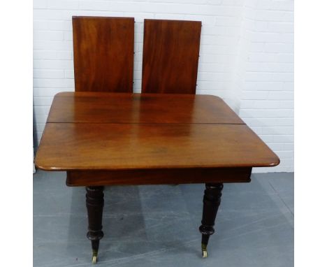 A Victorian mahogany extending dining table, on turned supports with brass caps and ceramic castors, complete with an extra t