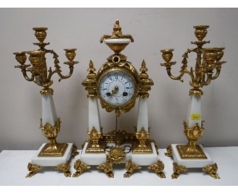 A three piece French white marble and brass clock garniture, with enamelled dial 