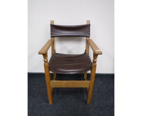An antique oak armchair upholstered in brown button leather 