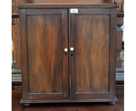 A 20th century mahogany table-top cabinet, moulded top with three quarter gallery above a pair of panel doors enclosing an ad