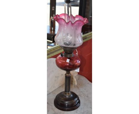 A Victorian Cranberry and clear glass oil lamp, Cranberry reservoir etched shade, gilt metal column, pottery foot 