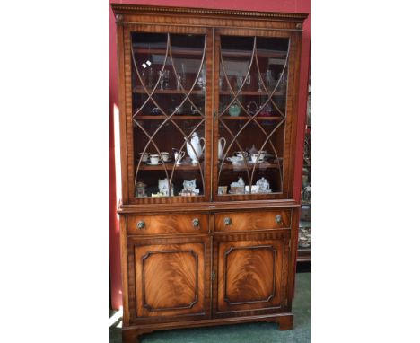 A reproduction mahogany bookcase, outswept dentil cornice above a pair of glazed doors enclosing an arrangement of adjustable