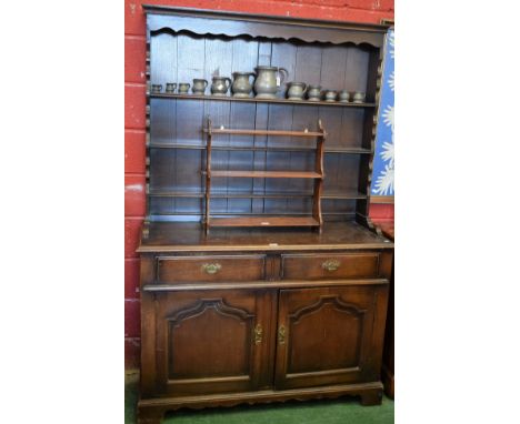 A 20th century oak dresser, outswept cornice above a shaped apron and three plate racks, the protruding base with two short d