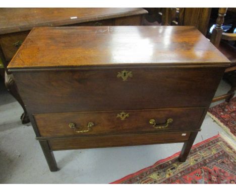 George III mahogany trunk with a hinged cover above a single drawer with brass handles and escutcheons mounted on a later bas