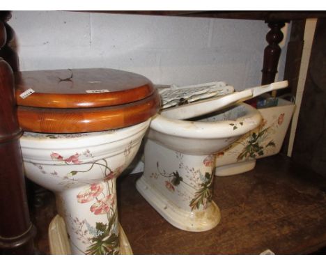 White ceramic floral decorated toilet and bidet together with a modern shower head