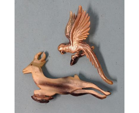 A painted horn brooch in the form of a parrot, 73mm and a horn brooch in the form of a leaping antelope, (2). 