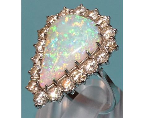 An impressive opal and diamond cluster ring claw-set a large opal of pear drop shape, 21 x 27mm, within surround of eighteen 