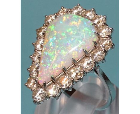 An impressive opal and diamond cluster ring claw-set a large opal of pear drop shape, 21 x 27mm, within surround of eighteen 