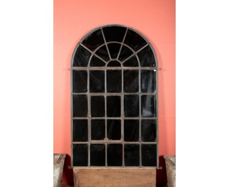 AN ARCHITECTURAL CAST IRON GARDEN MIRRORwith arched top and thirty-one panes, a hinged four pane panel to the centre, 175cm h