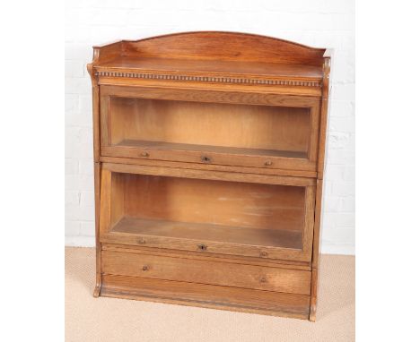 A 1930S LEBUS OAK TWO TIER SECTIONAL BOOKCASEwith arched gallery top and dentil frieze, the two sections with glazed rising f