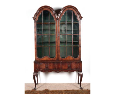 A QUEEN ANNE STYLE WALNUT CABINETthe upper section with a double domed top over glazed cupboard doors opening to shelves, the