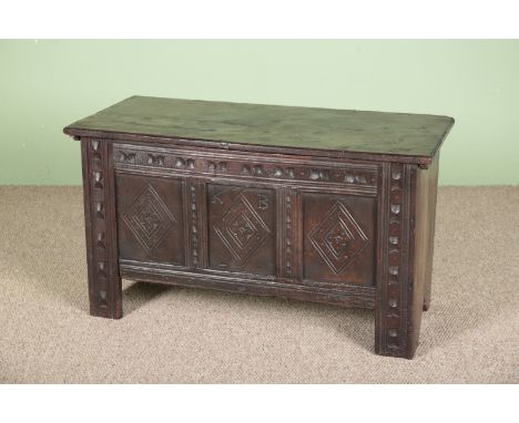 AN OAK COFFERthe hinged lid opening to a vacant interior, the front carved with lozenge panels and the initials 'K B', 55cm h