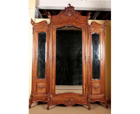 A FRENCH WALNUT TRIPLE WARDROBE with an ornately carved cornice over three mirrored cupboards, on short cabriole legs, 262cm 